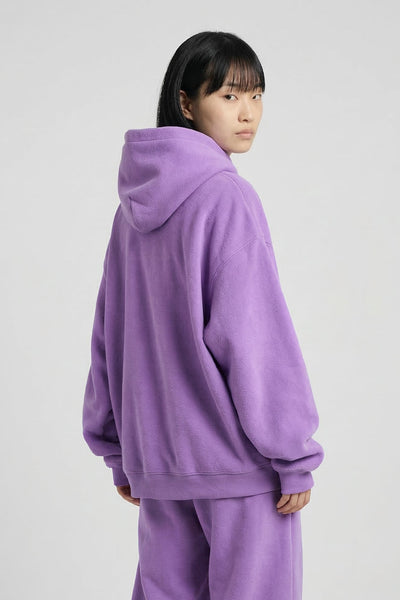 Person wearing a purple hoodie and pants set on a white background