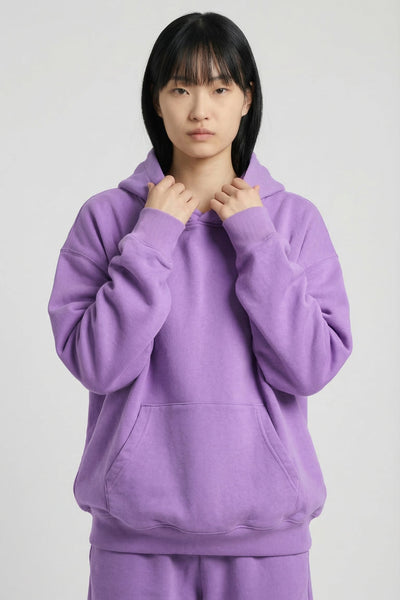 Person wearing a purple hoodie and pants on a white background