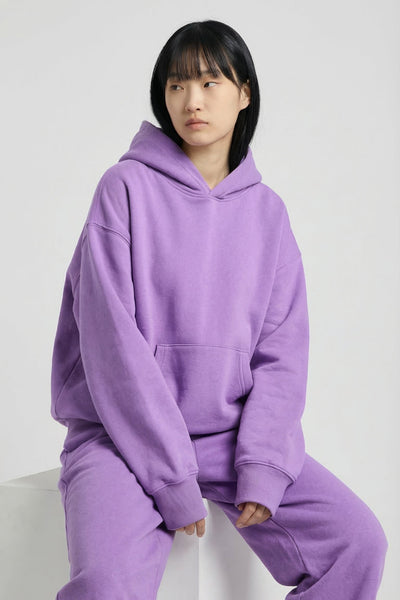 Person wearing a purple hoodie and pants on a white background