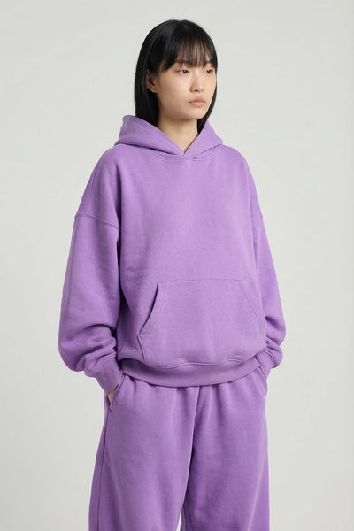 Person wearing a purple hoodie and pants set on a plain background