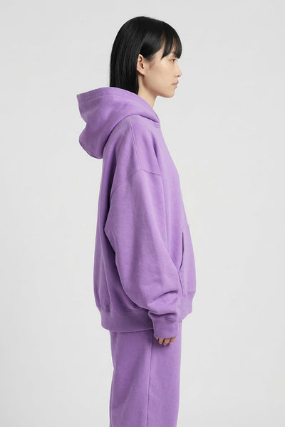 Person wearing a purple hoodie and pants on a white background