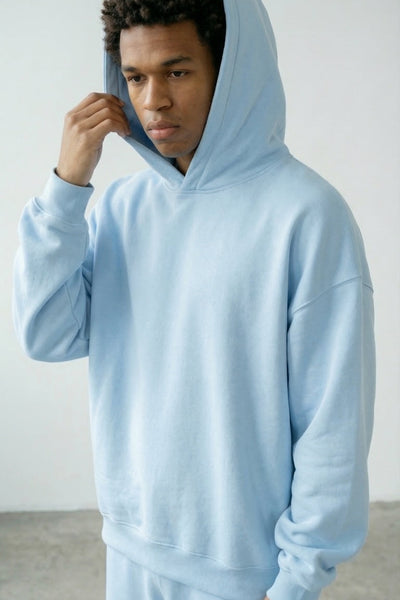 Person wearing a light blue hoodie and pants against a plain background