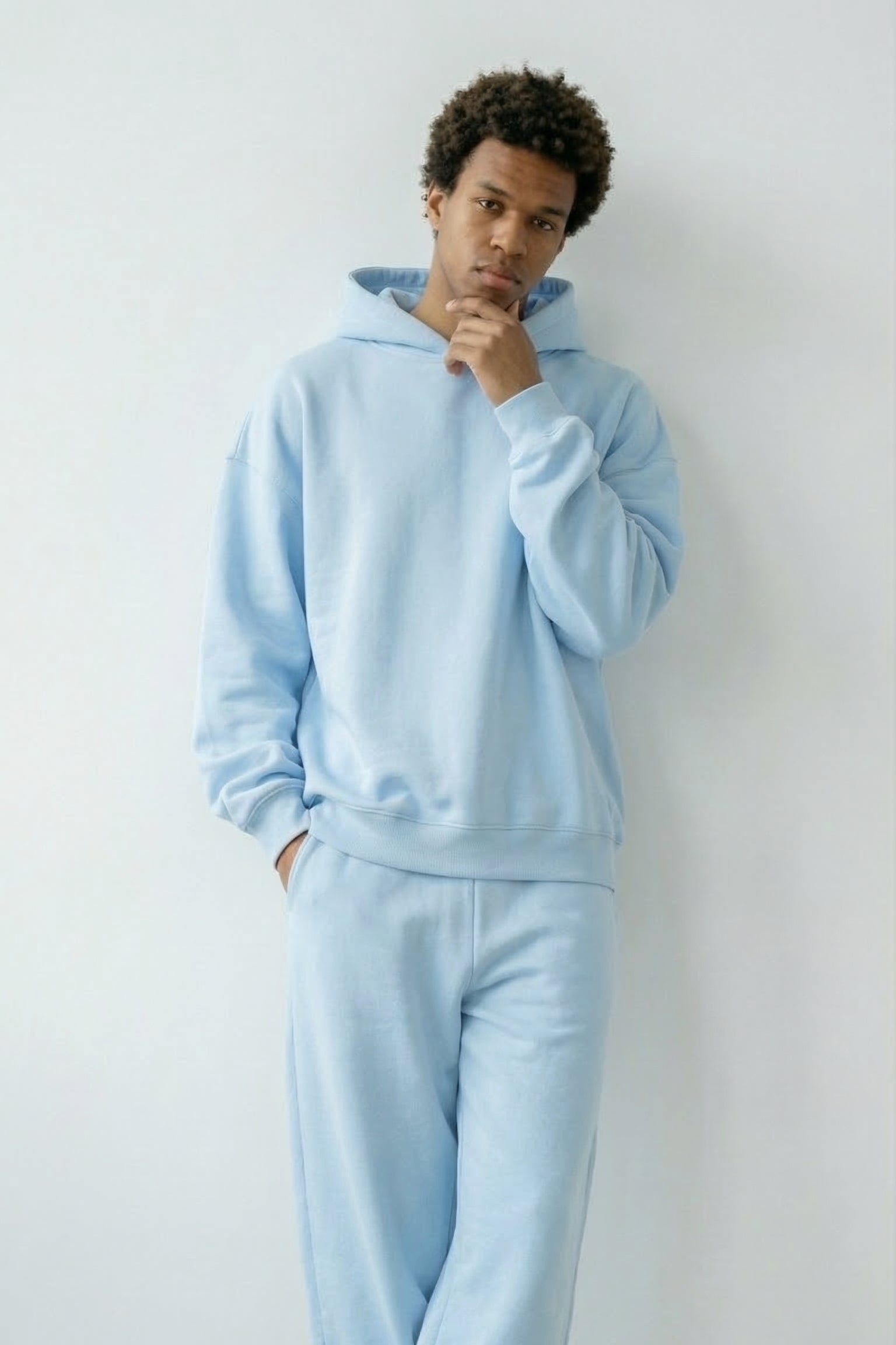 Person wearing a light blue tracksuit against a white background