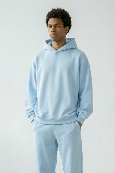 Person wearing a light blue hoodie and pants set on a plain background