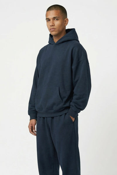 Man wearing a navy blue hoodie and pants set on a white background