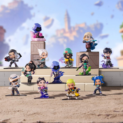 A set of 12 chibi-style collectible figurines from the game Genshin Impact, displayed on a sandy beach-themed miniature set with stone platforms and a blue sky background.