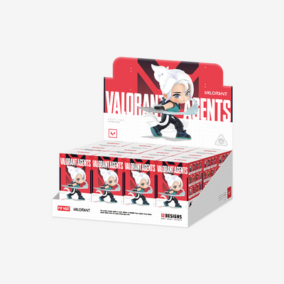 A retail display box filled with multiple 'Valorant Agents' blind packs by 12DESIGNS, featuring a large character graphic on the display backboard and individual packs lined up in the front against a light gray background.
