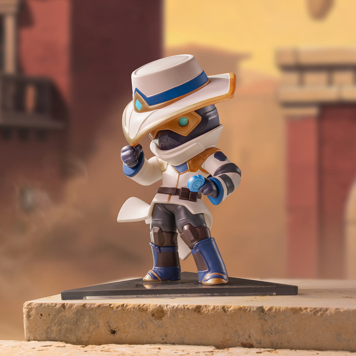 Cypher A stylized collectible figurine of a cowboy-themed character wearing a white hat with blue and gold trim, a white coat, and blue-and-gray boots, posed on a black display base against a blurred desert-like architectural background.