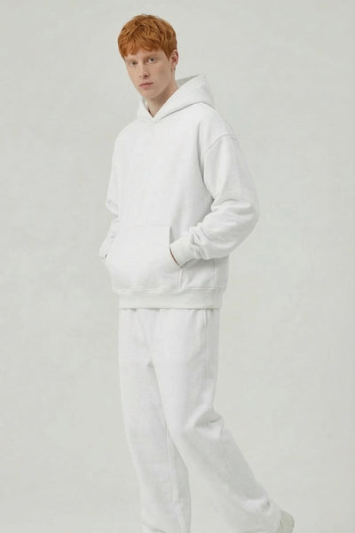 Person wearing a white hoodie and pants on a light gray background