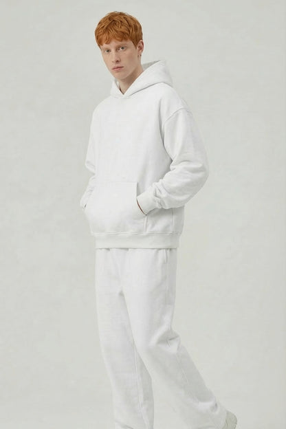 Person wearing a white hoodie and pants on a light gray background