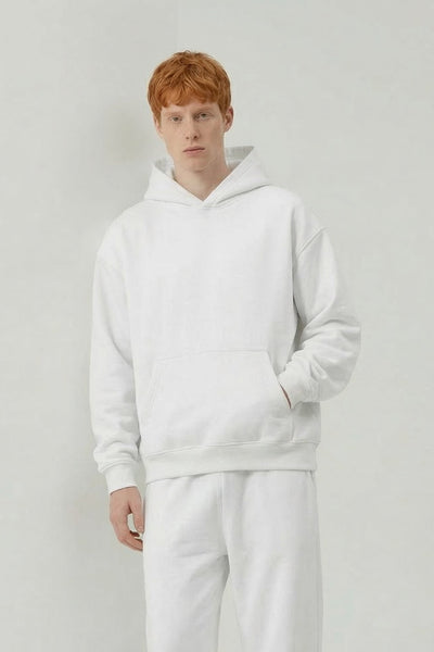 Person wearing a white hoodie and pants on a plain background