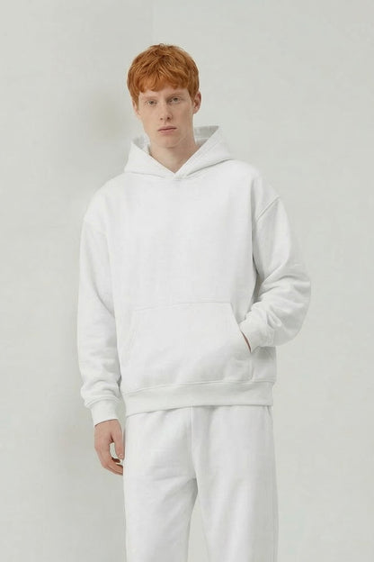 Person wearing a white hoodie and pants on a plain background