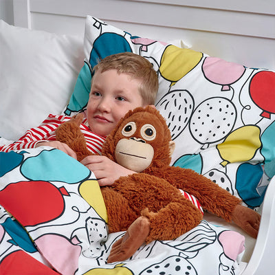 Brown plush monkey held on a bed, with large eyes and felt white muzzle