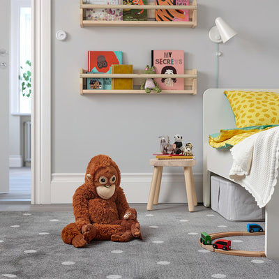 Brown plush monkey sitting on carpet, friendly face with white muzzle