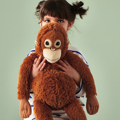 Brown plush monkey held close to face, big eyes and white muzzle detail