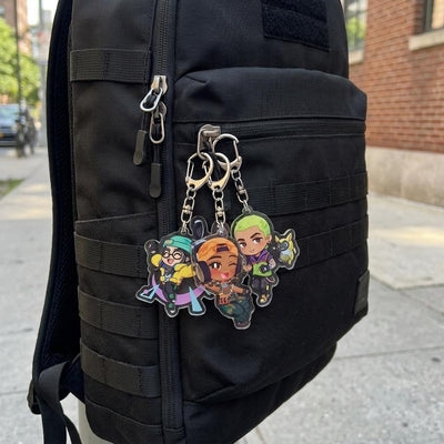 Chibi acrylic keychains attached to a black backpack with metal clips