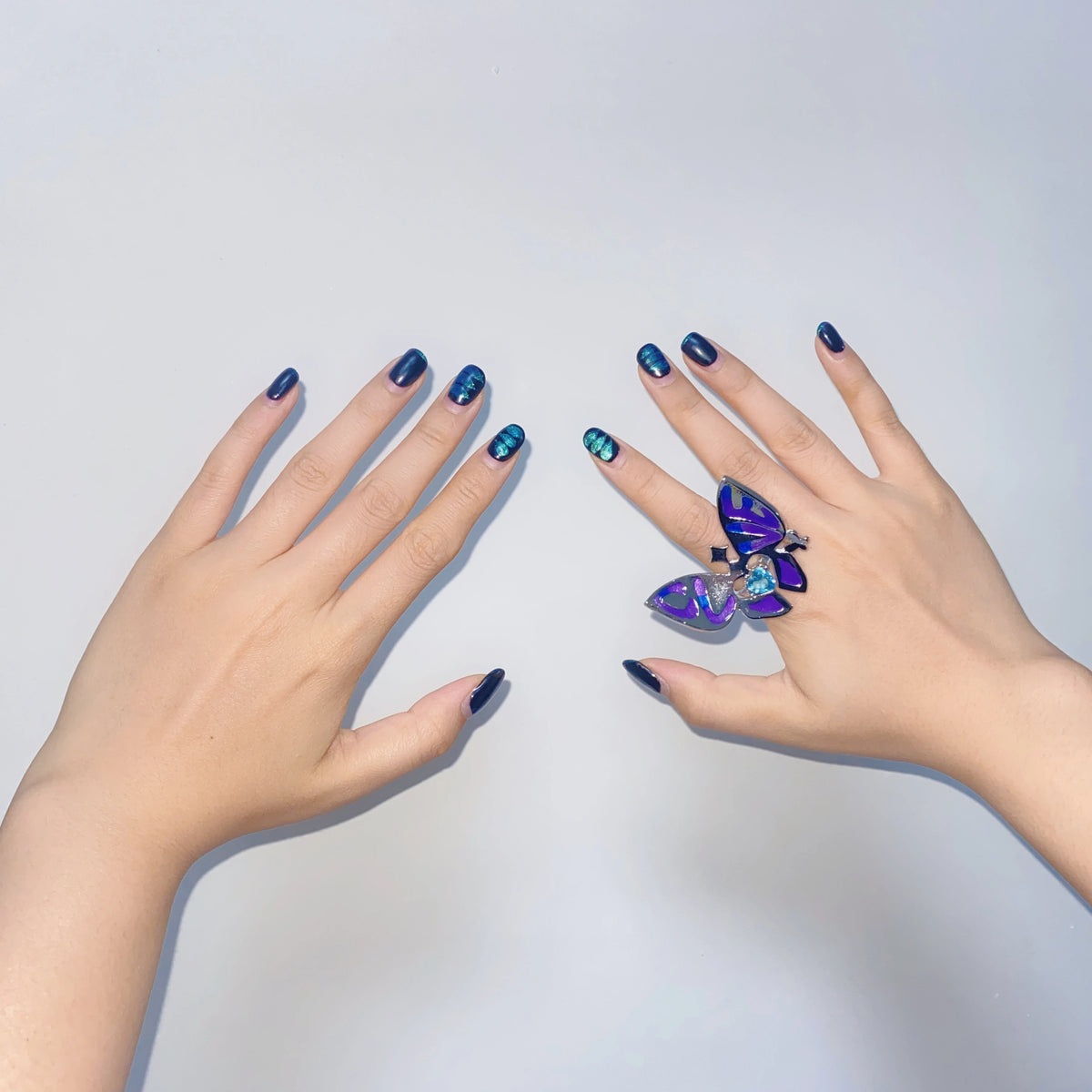 Blue enamel butterfly ring with heart crystal on finger, silver band