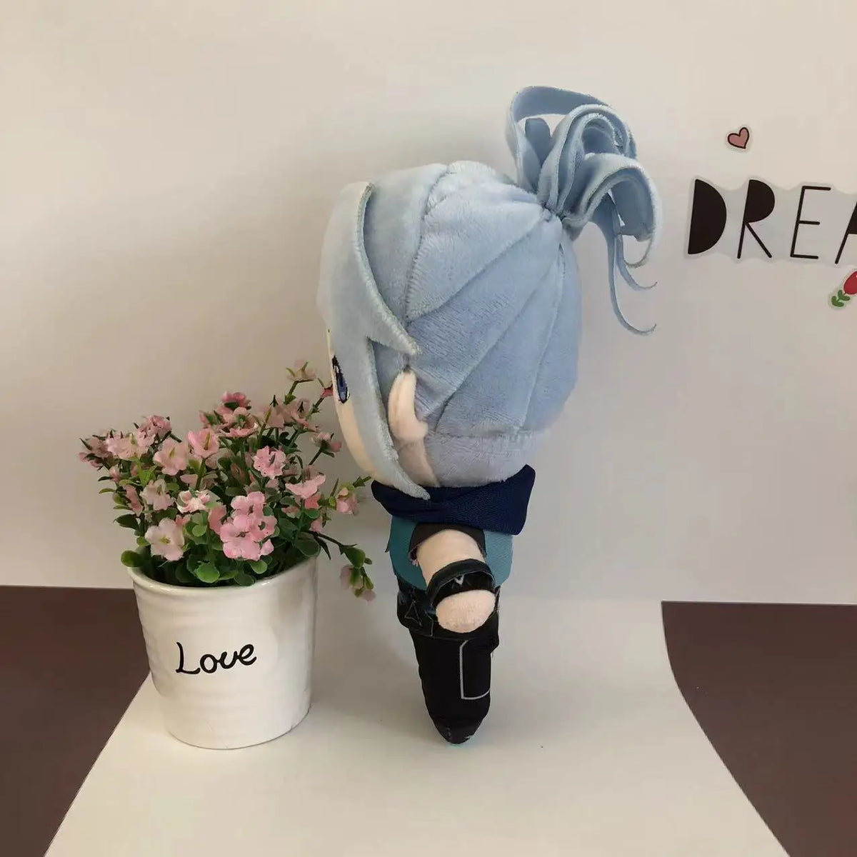 Light blue plush doll side view with teal top, black shoes, and bow detail