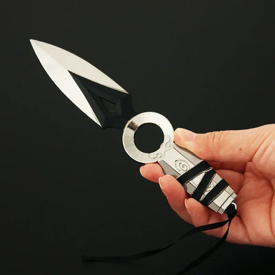 Kunai knife keychain held in hand, white double-blade with cutout detail and silver ring