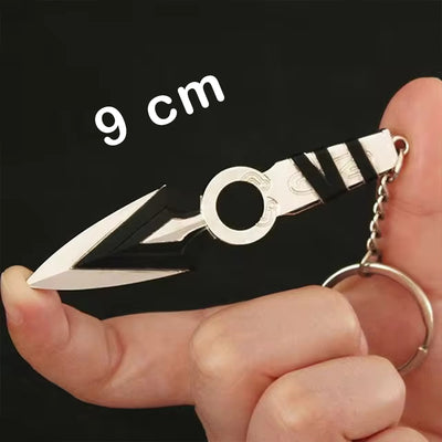 Kunai knife keychain with black-and-white handle and metal ring, held in hand