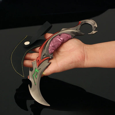 Karambit knife with red handle, silver blade, and green graphic accents in hand
