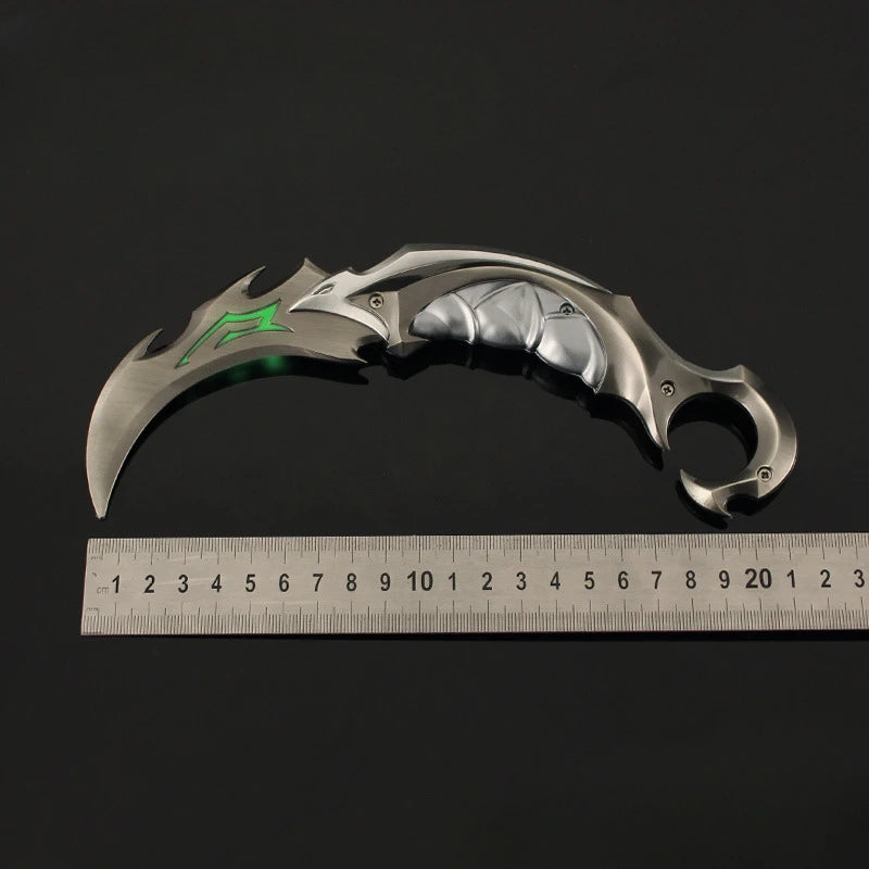 Karambit knife with silver blade and green accent markings, next to a ruler