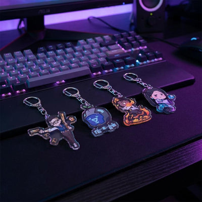 Acrylic keychain charms shaped like chibi agents on a desk keyboard