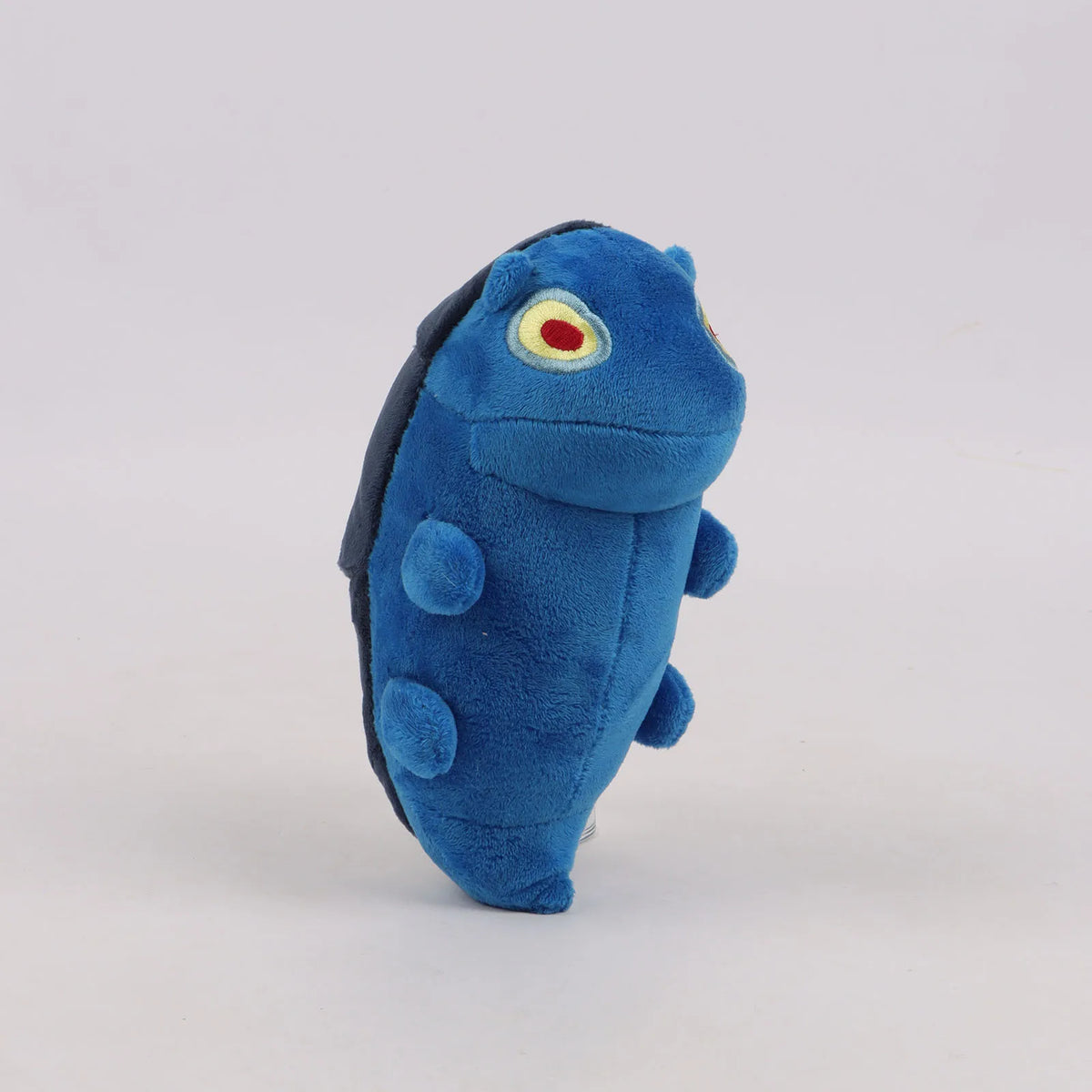 Blue plush toy with small arms and a red-and-yellow eye emblem, side view.
