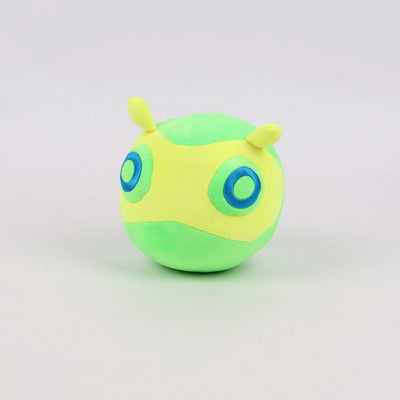 Green round plush toy with small yellow horns and blue circular eyes.